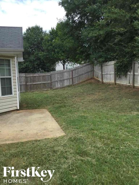 a backyard with a fence and a yard and a house