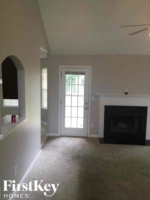 an empty living room with a fireplace and a white door