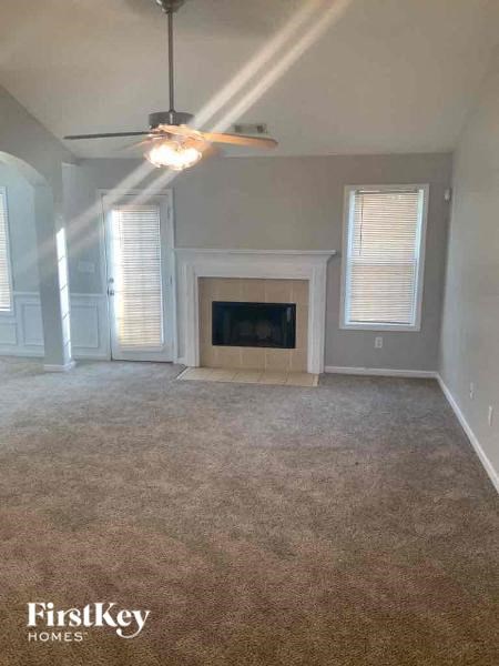 an empty living room with a fireplace and a ceiling fan