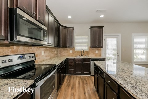 A kitchen with dark brown cabinets and a granite countertop.