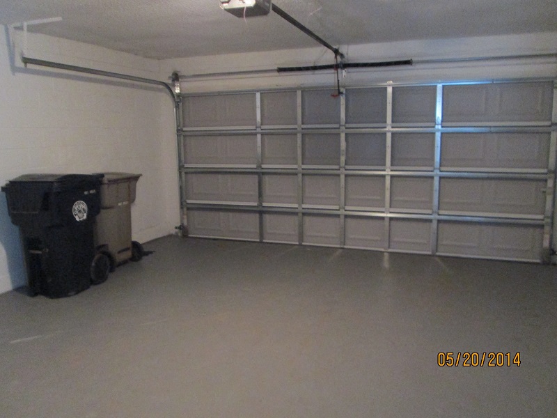 the inside of a garage with white walls and a dumpster