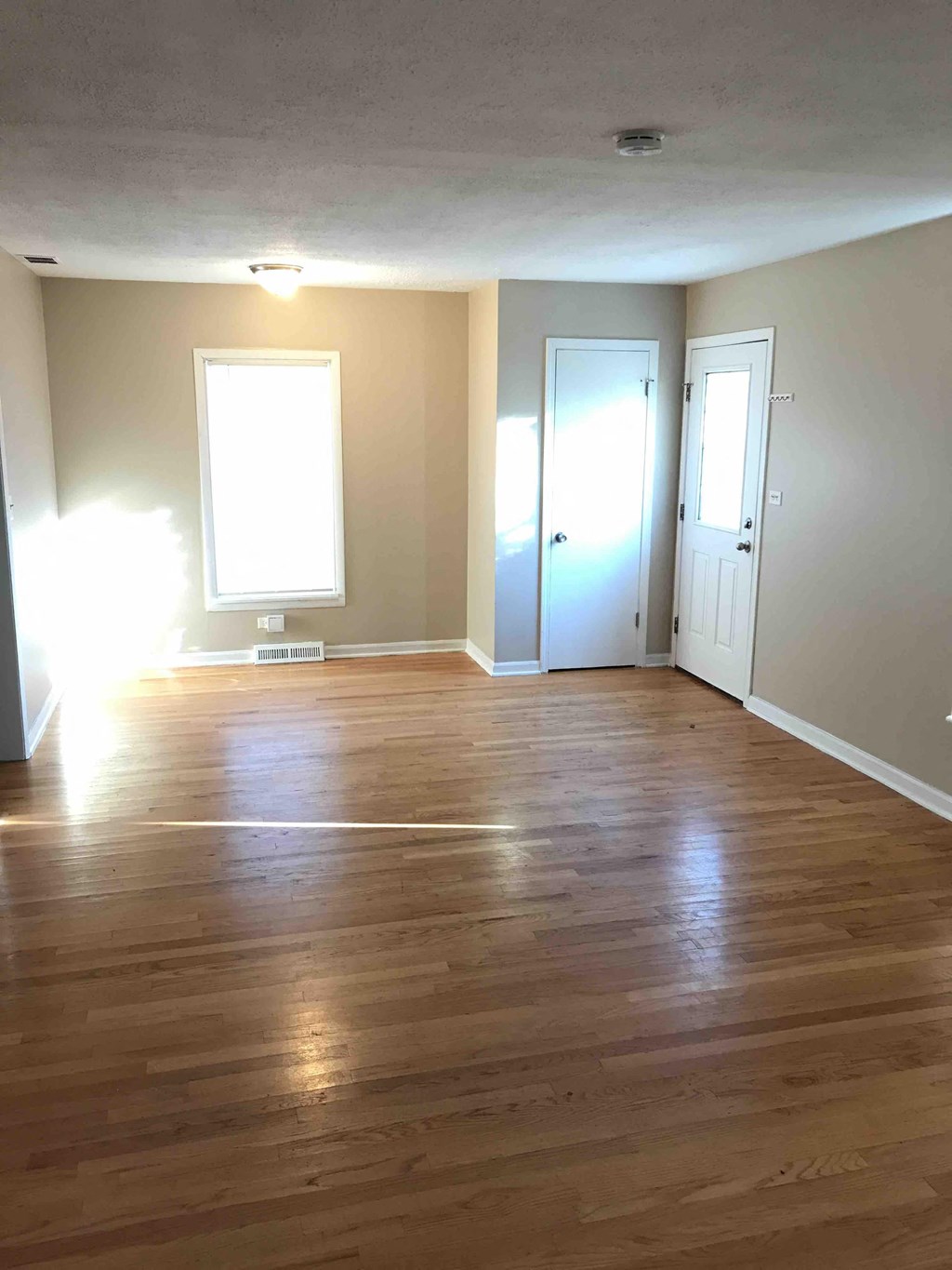 an empty living room with wooden floors and a window