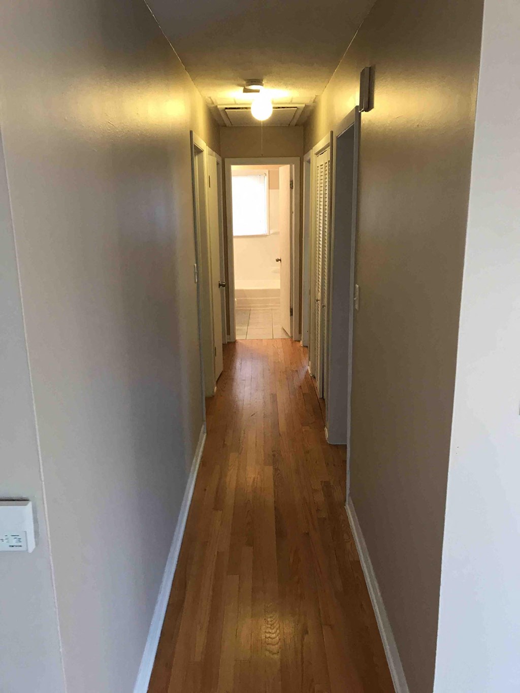 a hallway with a hard wood floor and a door to a closet