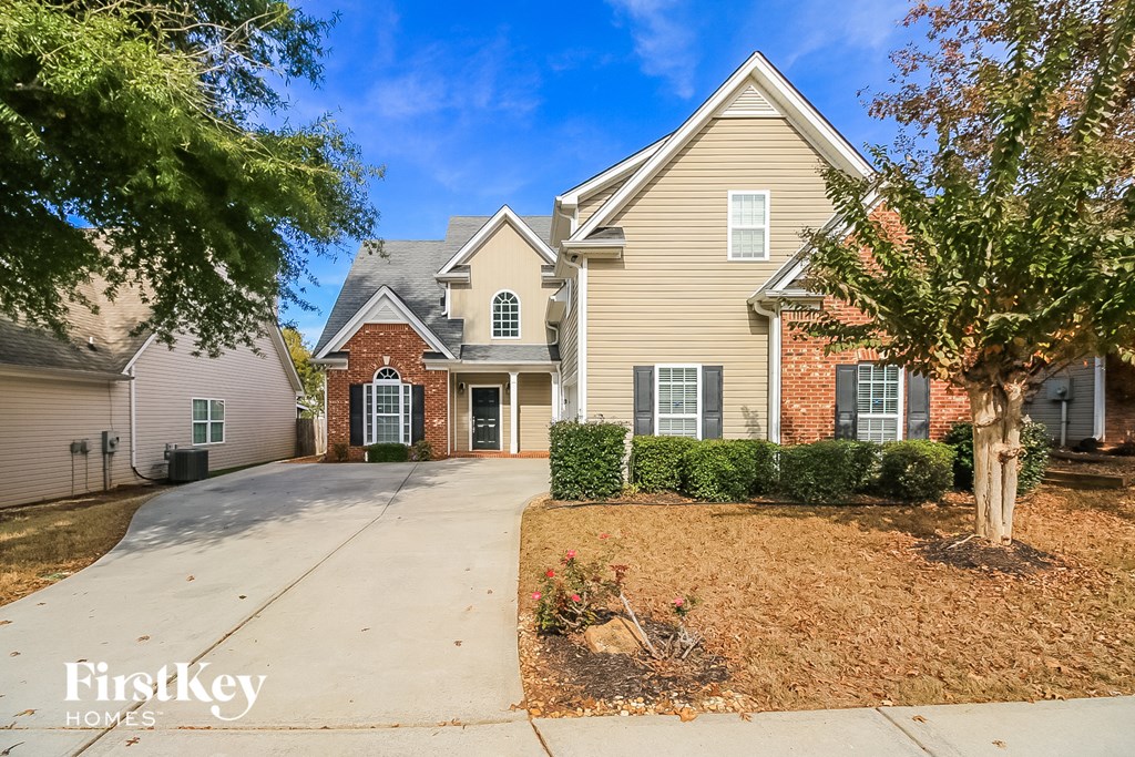 A house with a driveway and a tree in front of it.