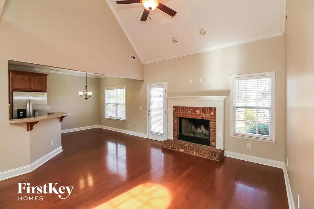 A spacious living room with a fireplace and a ceiling fan.