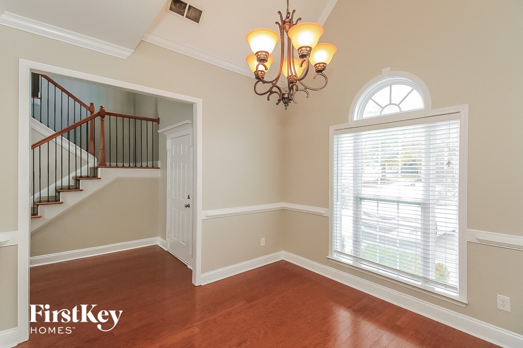 A well-lit room with a chandelier and a window with blinds.