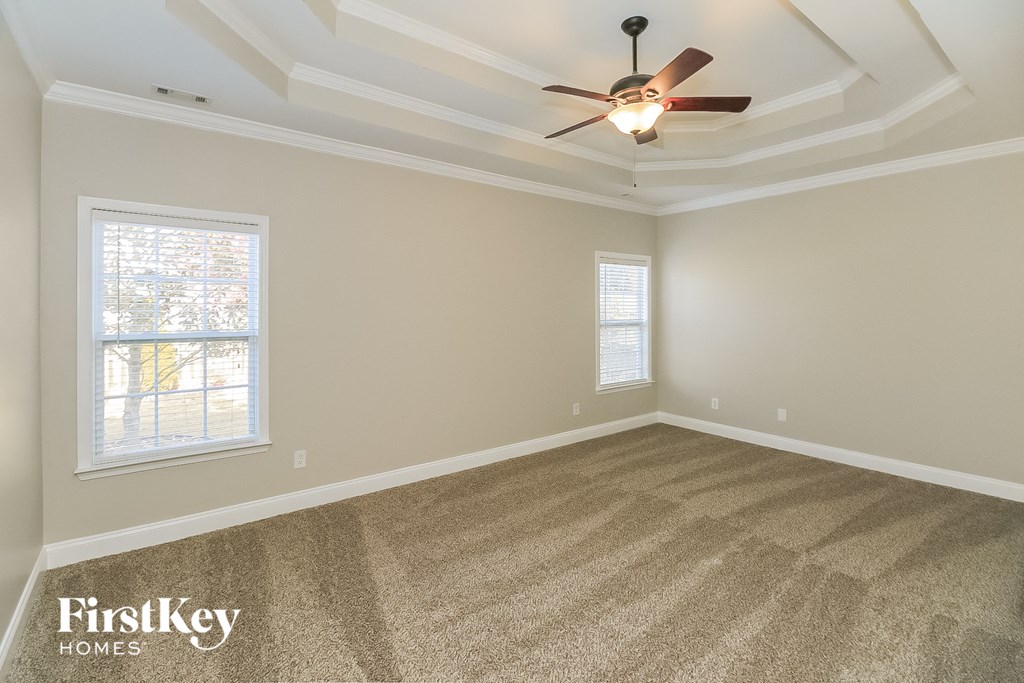 A room with a carpeted floor and a ceiling fan.