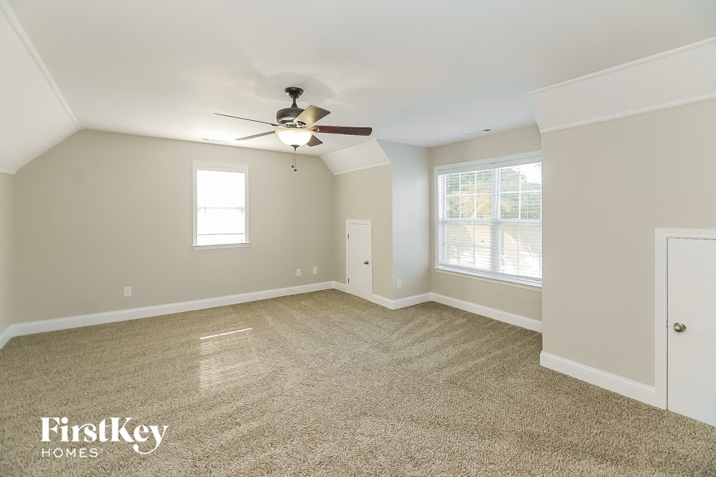A spacious room with a carpeted floor and a ceiling fan.