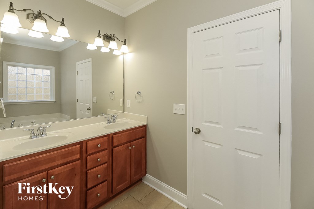 A bathroom with a white door and a mirror above a sink.