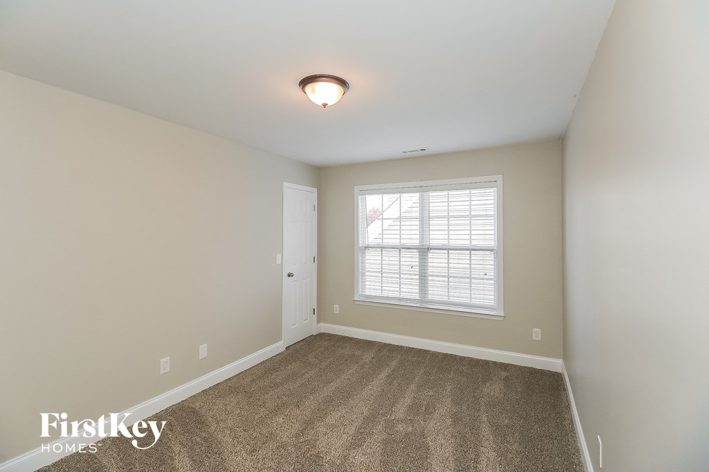 A room with a carpeted floor and a window with blinds.