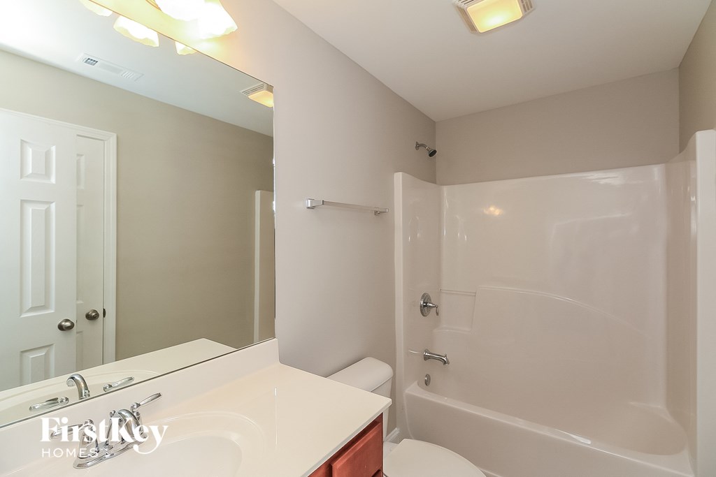A white bathroom with a tub, sink, and mirror.