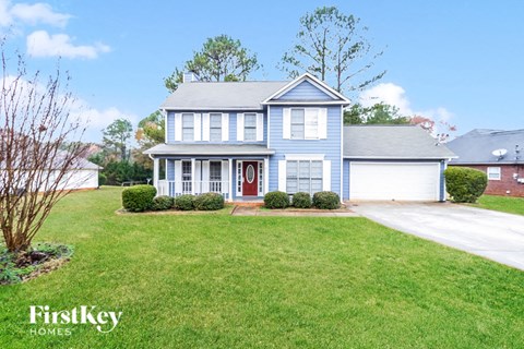 A blue house with a red door and a white garage door.
