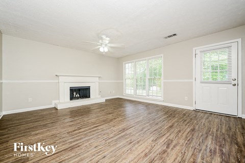 A spacious room with a fireplace and wooden flooring.