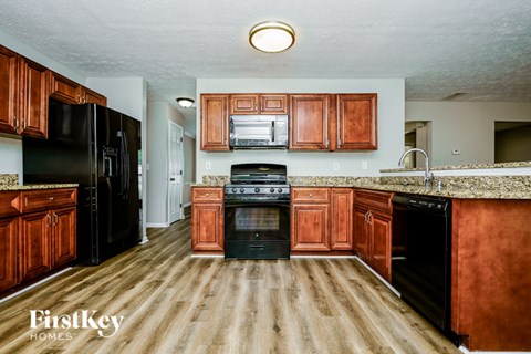 A kitchen with wooden cabinets and a black refrigerator.