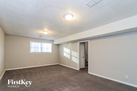 the spacious living room with carpeting and a door to the hallway