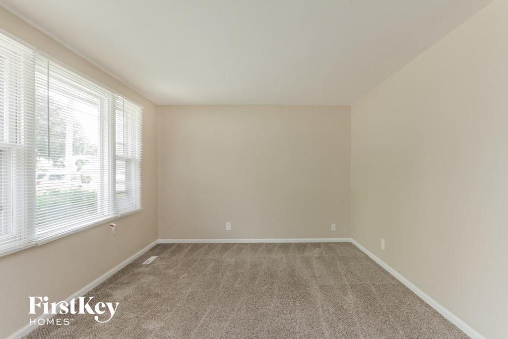 A room with a carpeted floor and a window with blinds.