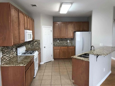 A kitchen with brown cabinets and a granite countertop.