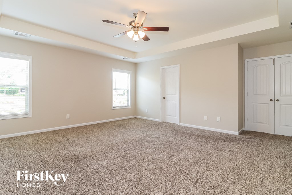 an empty living room with a ceiling fan and white doors