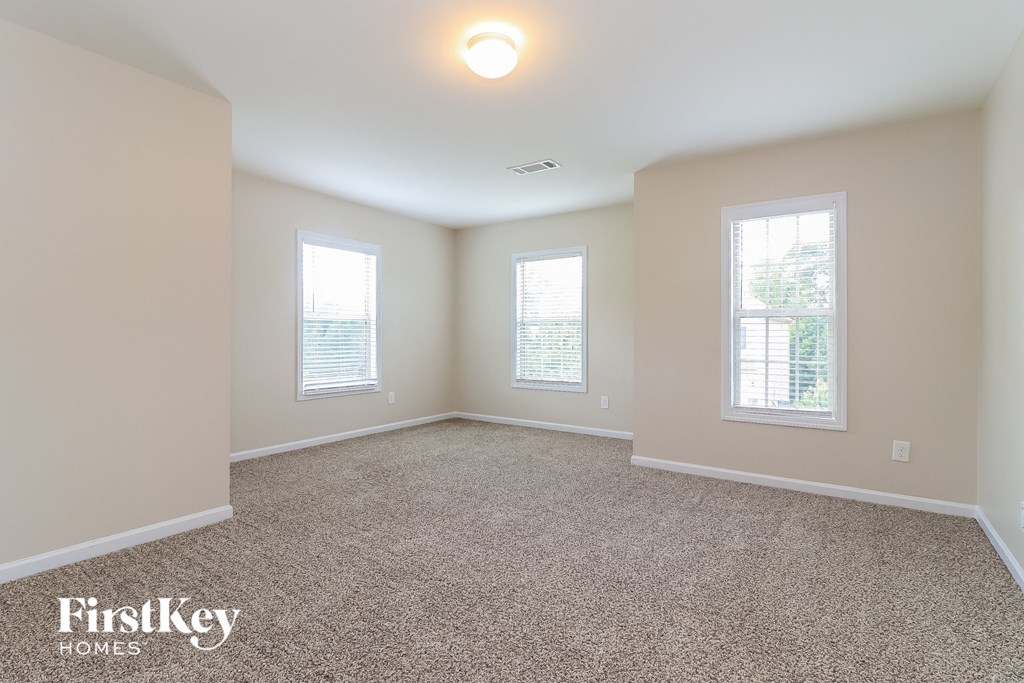 an empty room with three windows and a carpeted floor