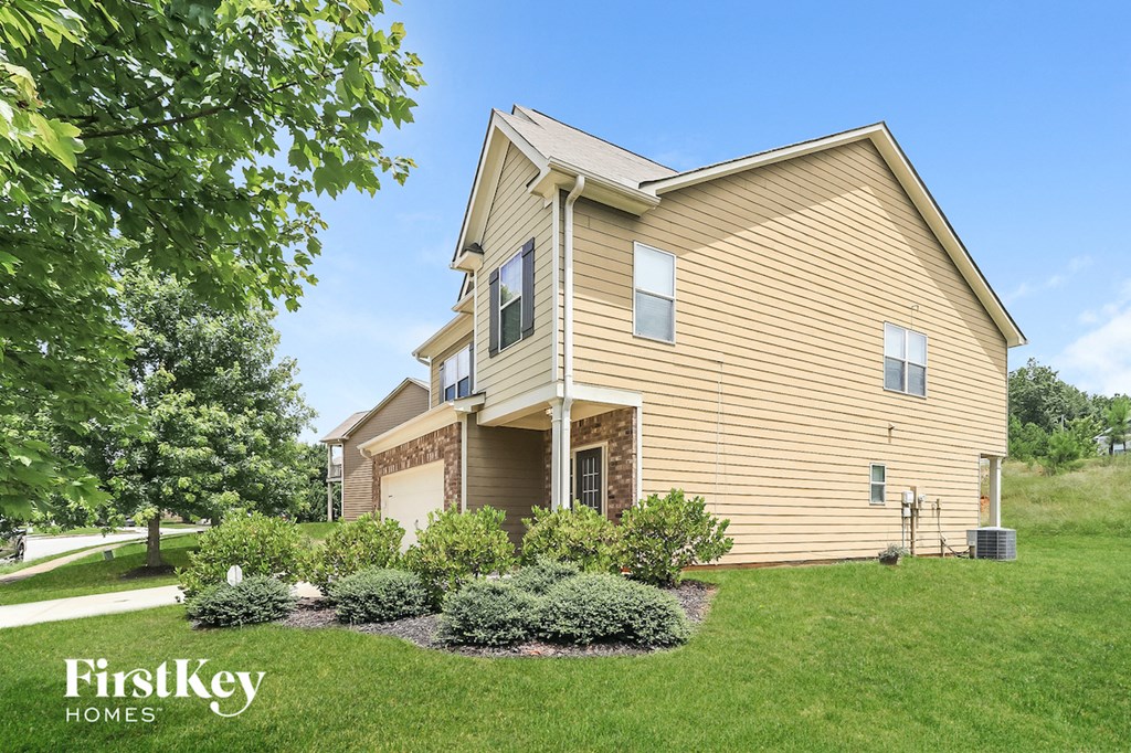 a home with yellow siding and green grass and trees