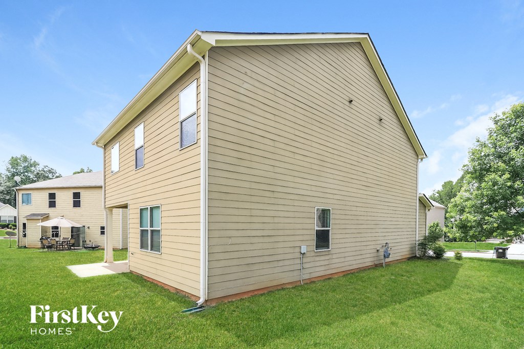 the backyard of a house with a green lawn and a yellow house
