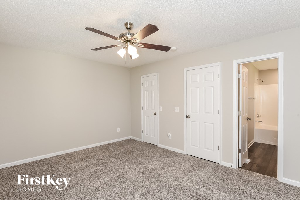 a bedroom with a ceiling fan and a door to a closet