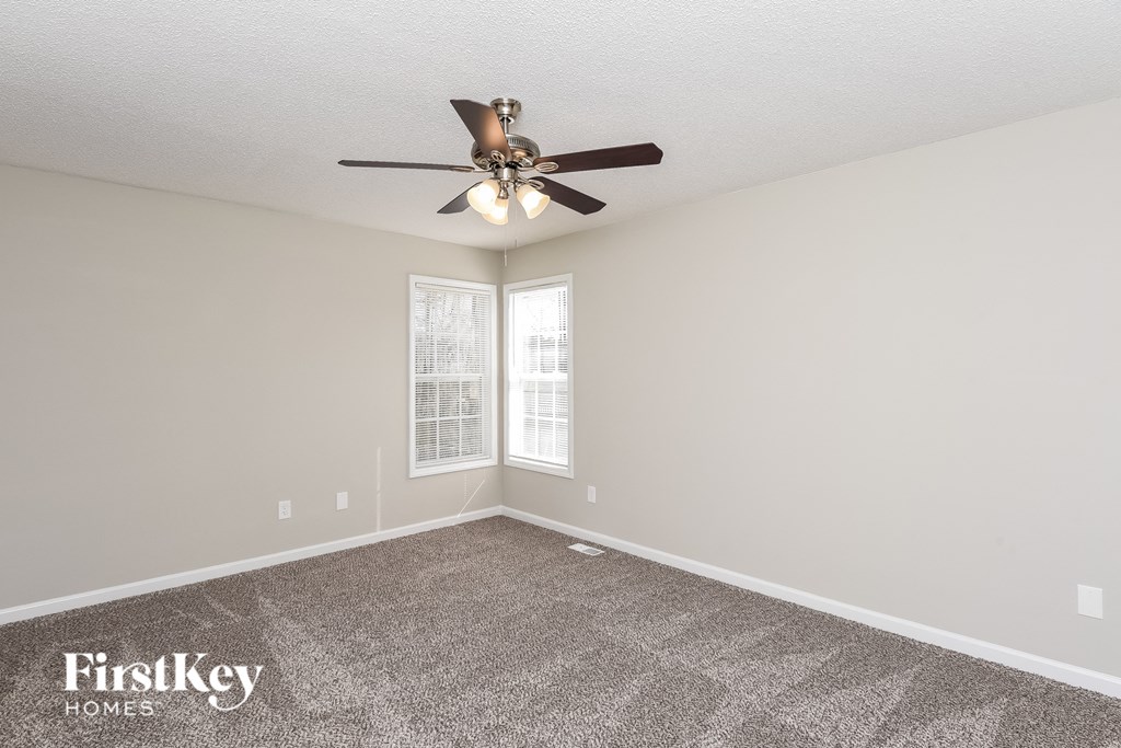 the spacious living room with ceiling fan and carpet