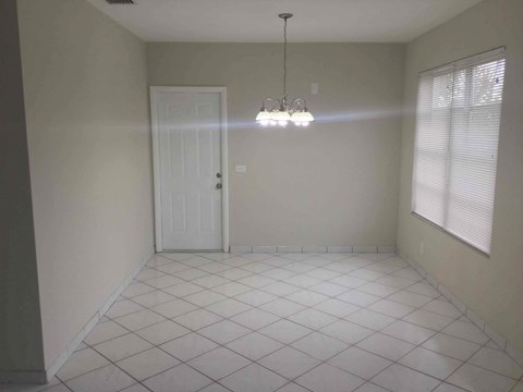 A room with a white door and a chandelier hanging from the ceiling.