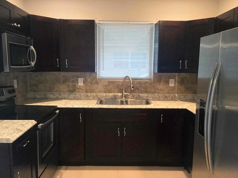 A kitchen with dark wood cabinets and a granite countertop.