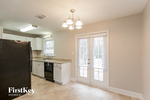 a kitchen with white cabinets and a black refrigerator and a sink