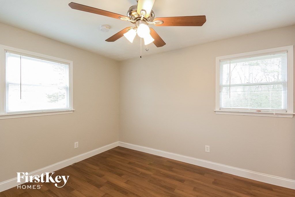 a bedroom with a ceiling fan and two windows