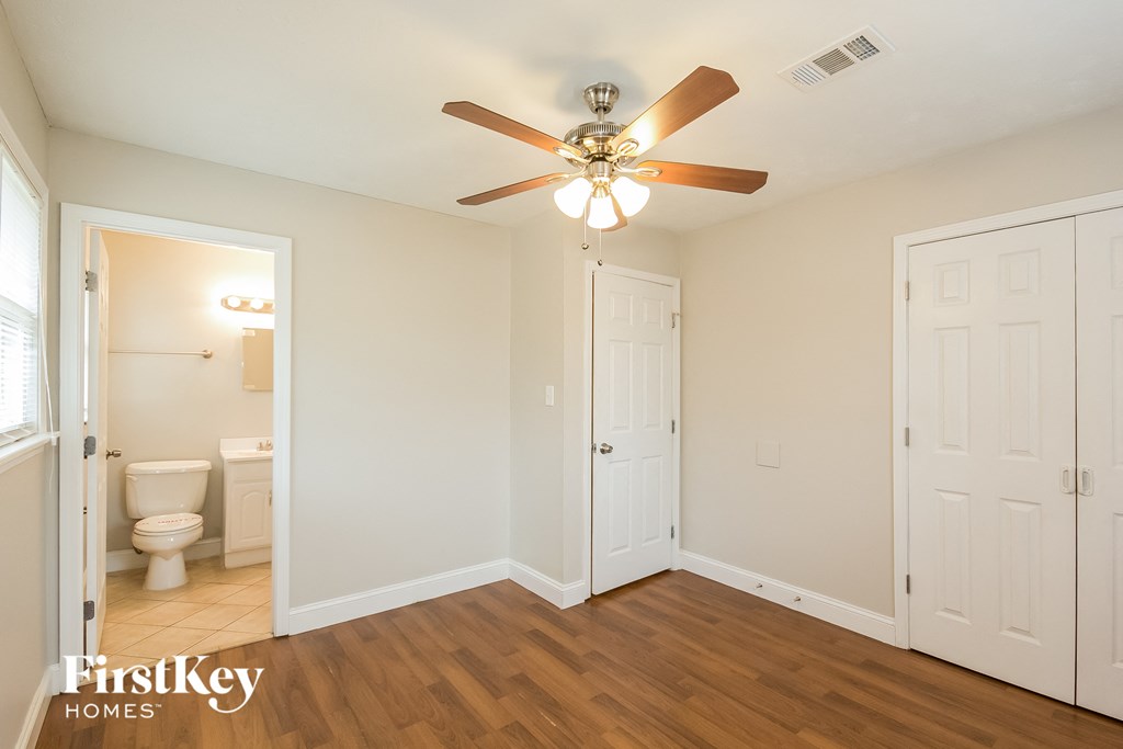 a bedroom with a ceiling fan and a door to a bathroom
