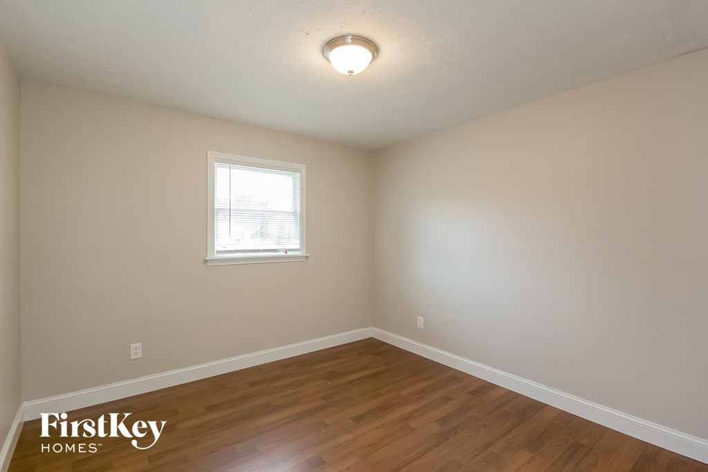 the spacious living room with hardwood flooring and a window