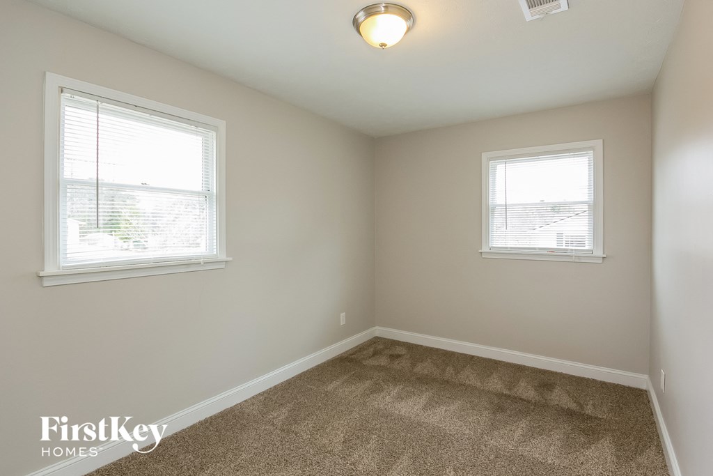 a bedroom with two windows and a carpeted floor