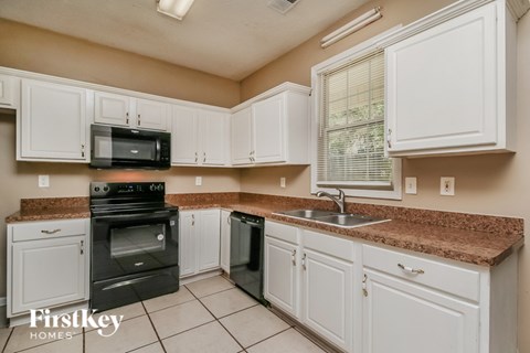 A kitchen with white cabinets and brown countertops.