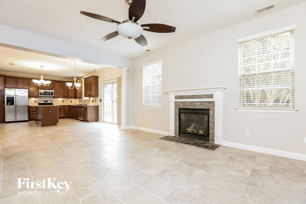 A spacious living room with a fireplace and a ceiling fan.