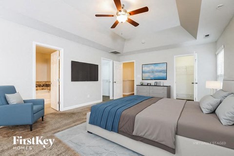 A bedroom with a large bed and a ceiling fan.