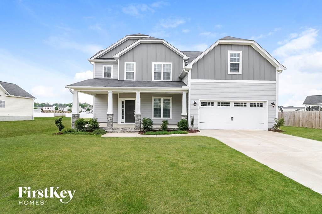 A grey house with a white garage door and a green lawn.
