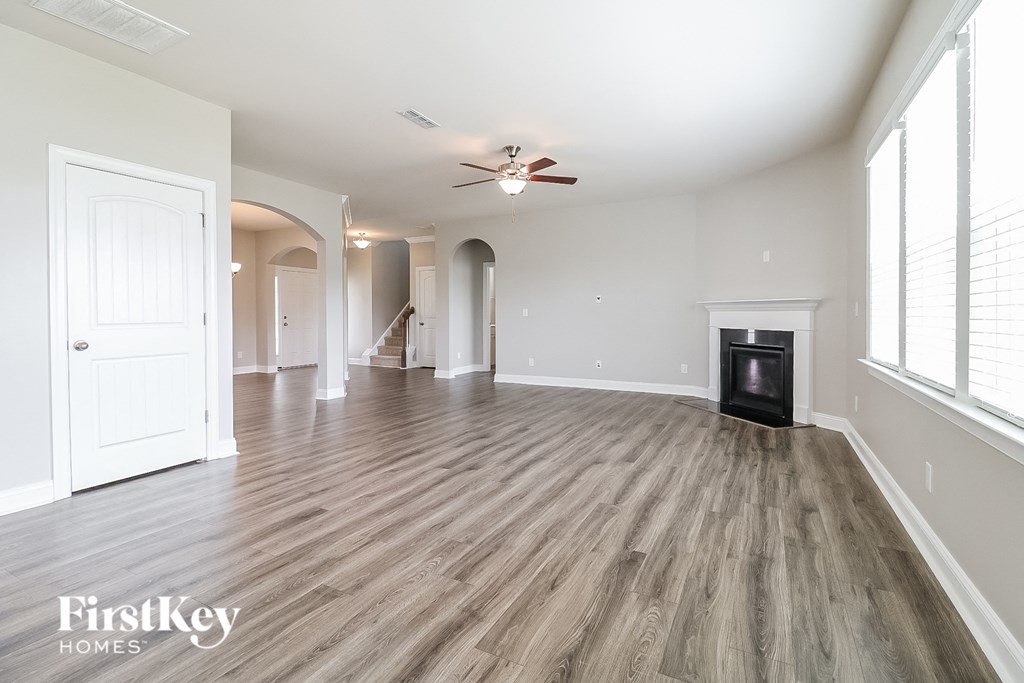 A spacious room with wood flooring and a ceiling fan.