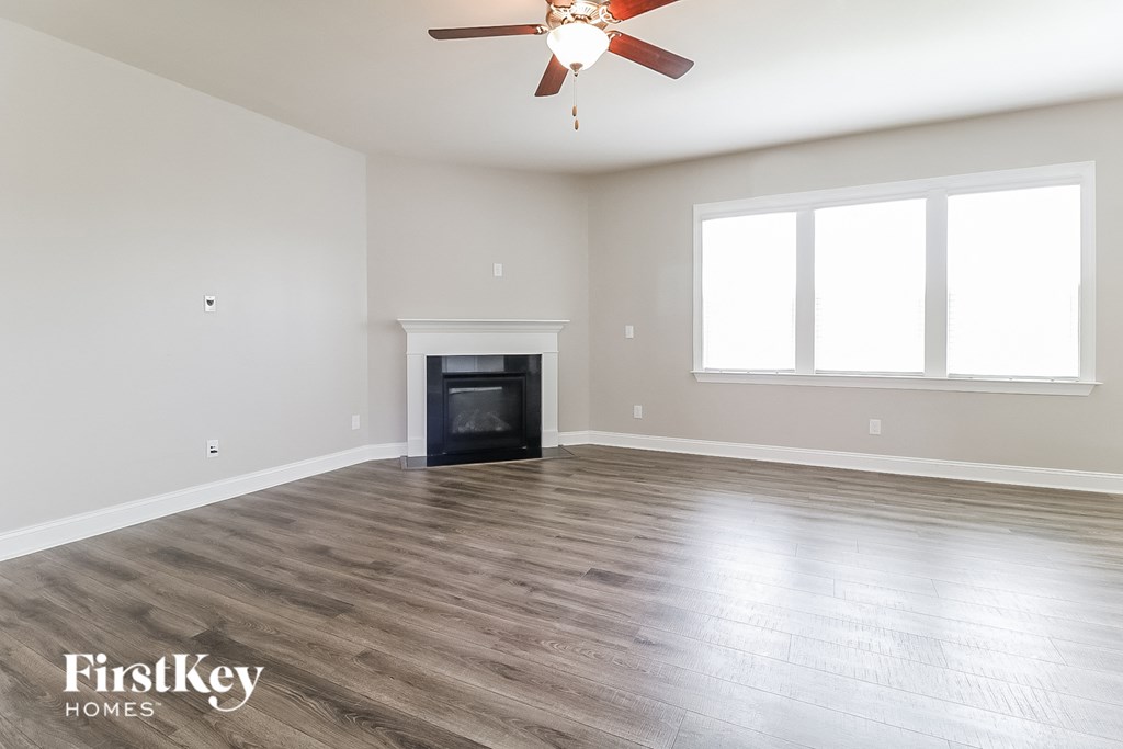 A spacious living room with a fireplace and a ceiling fan.