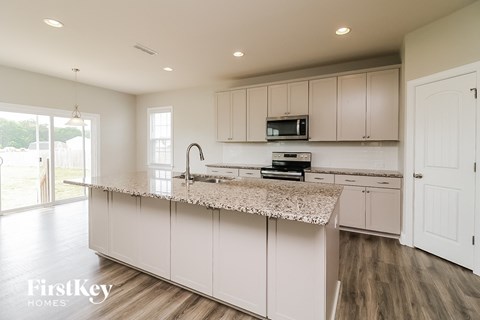 A kitchen with a granite countertop and a microwave above it.