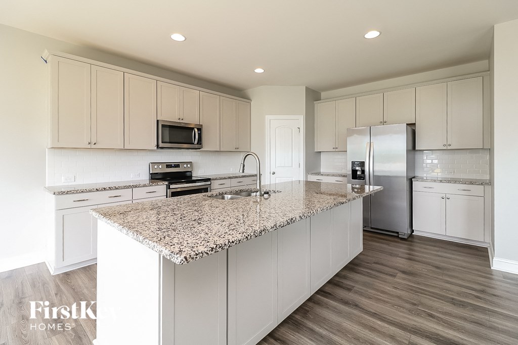 A kitchen with a granite countertop and stainless steel appliances.