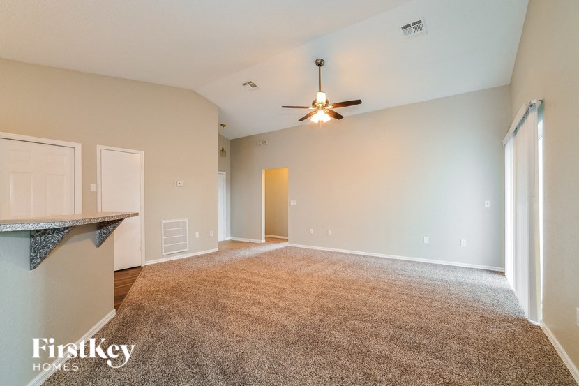 A spacious room with a carpeted floor and a ceiling fan.