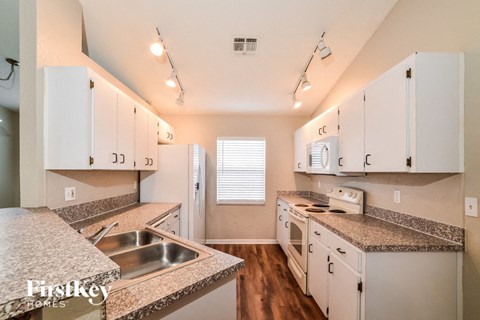 A kitchen with white cabinets and a granite countertop.