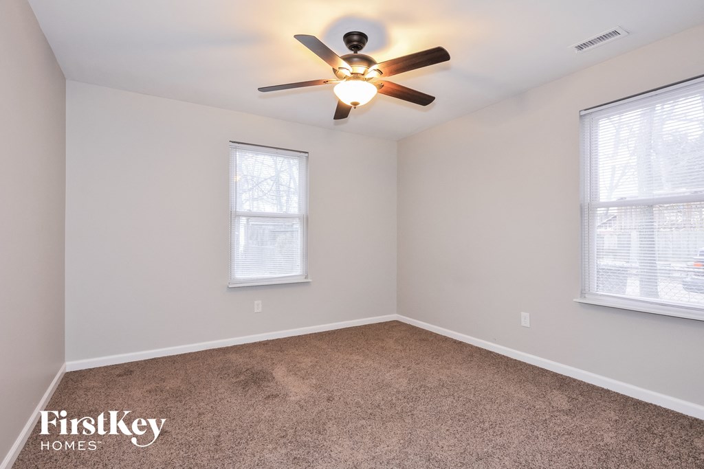 a bedroom with a ceiling fan and two windows