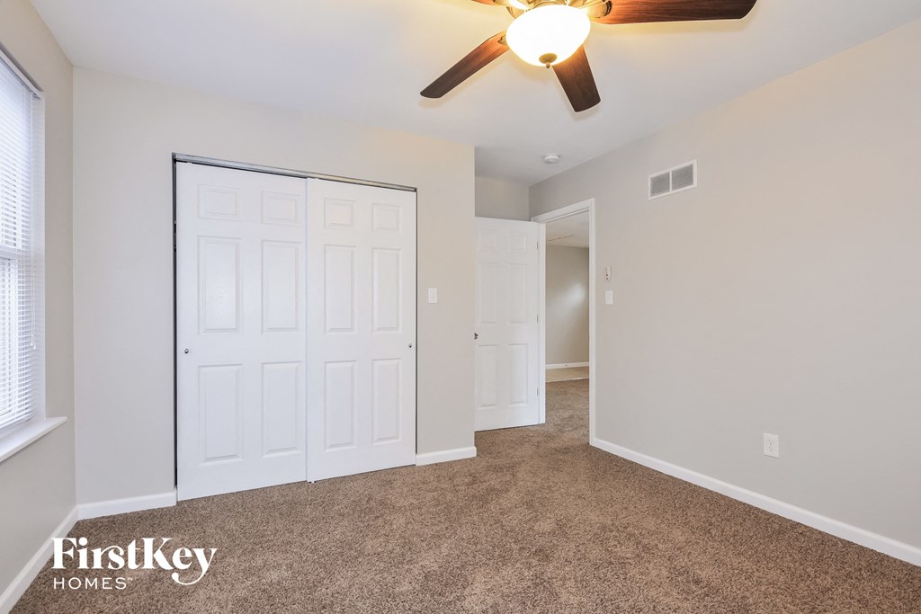 a bedroom with a ceiling fan and a door to a closet