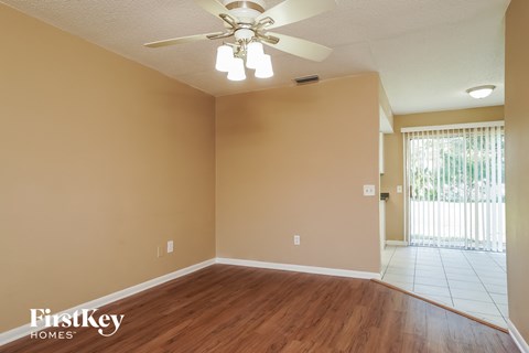 A room with a ceiling fan and light fixture, and a door leading to a balcony.