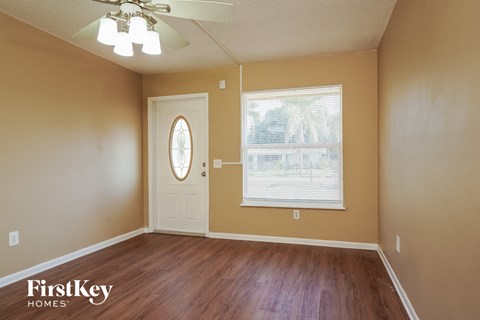 A room with a wooden floor and a window with blinds.