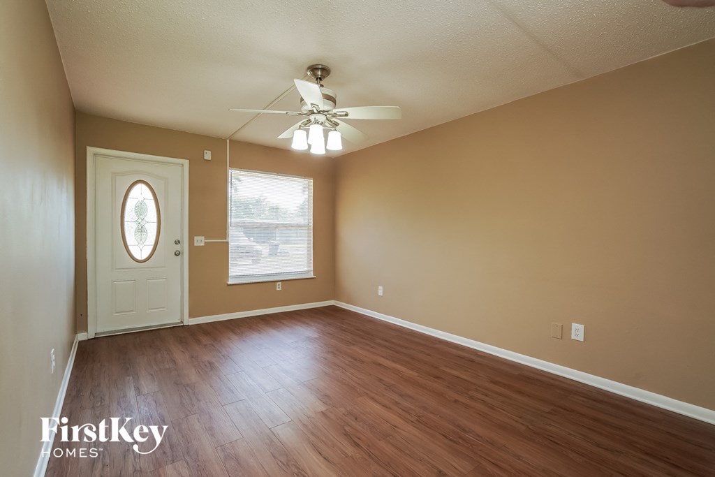 A room with a white door and a window with a view of a parking lot.