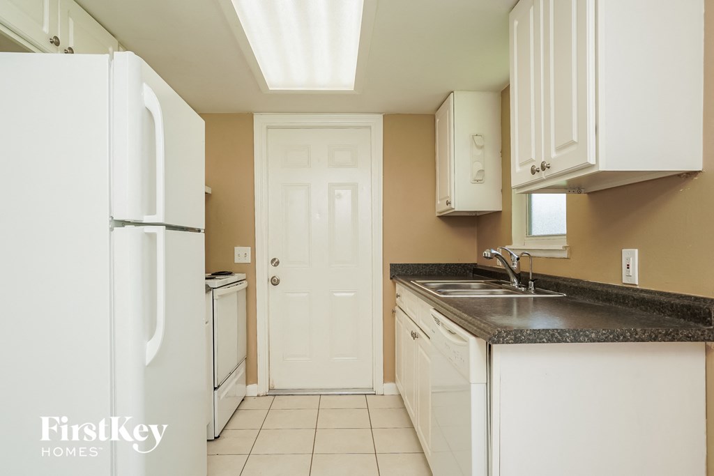 A kitchen with a white refrigerator and brown walls.